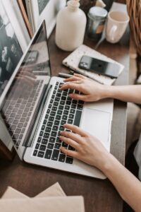 Vue d'en haut d'une femme méconnaissable assise à une table et tapant sur le clavier d'un ordinateur pendant un travail à distance dans un espace de travail moderne