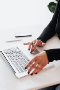 Les mains d'une femme d'affaires tapant sur un ordinateur portable dans un espace de travail lumineux et moderne.